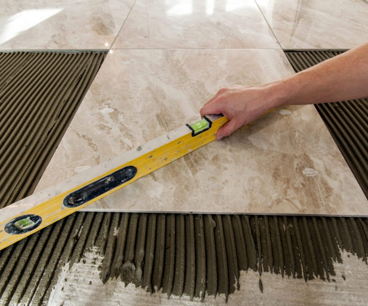 Ceramic tiles and tools for tiler. Floor tiles installation. Home improvement, renovation - ceramic tile floor adhesive, mortar, level