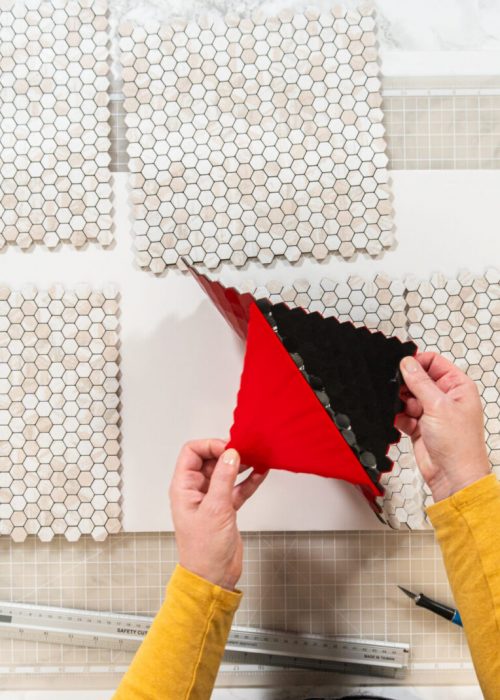 In the process of mounting peel and stick mosaic tiles onto a foam board, perfect for enhancing a food photography studio's aesthetic.