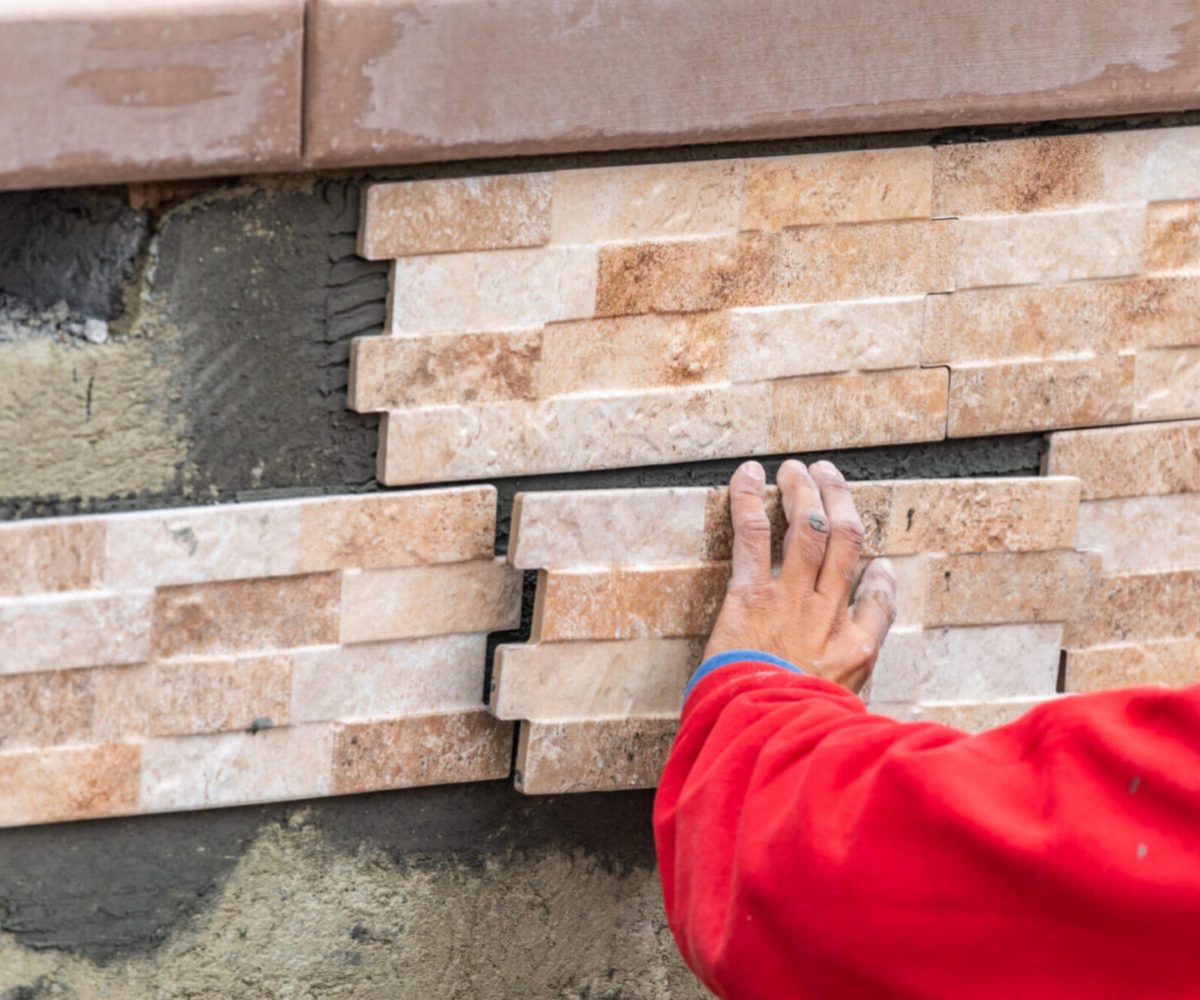 Worker Installing Wall Tile at Construction Site.