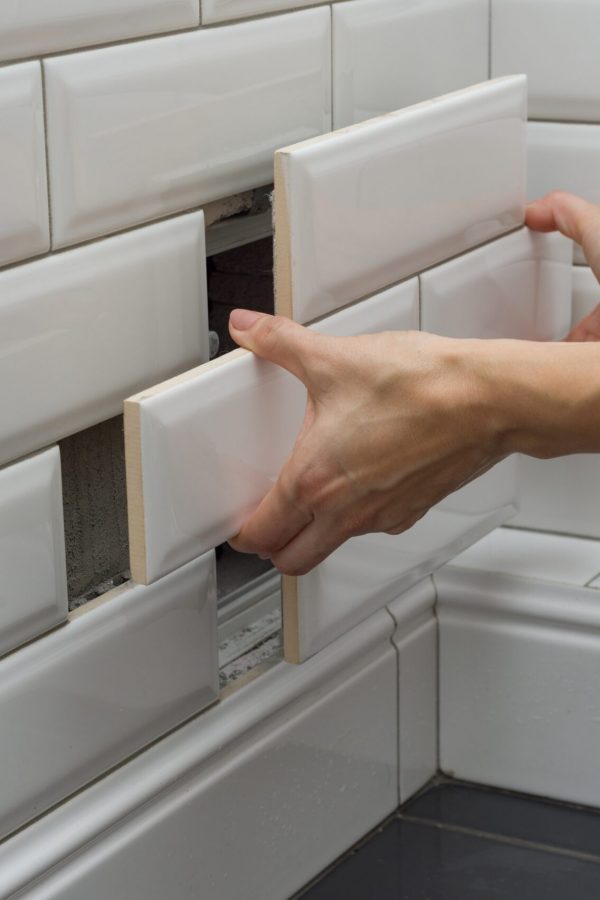 Woman opens, closes the hidden revision sanitary hatch on the wall of tile under the bathroom