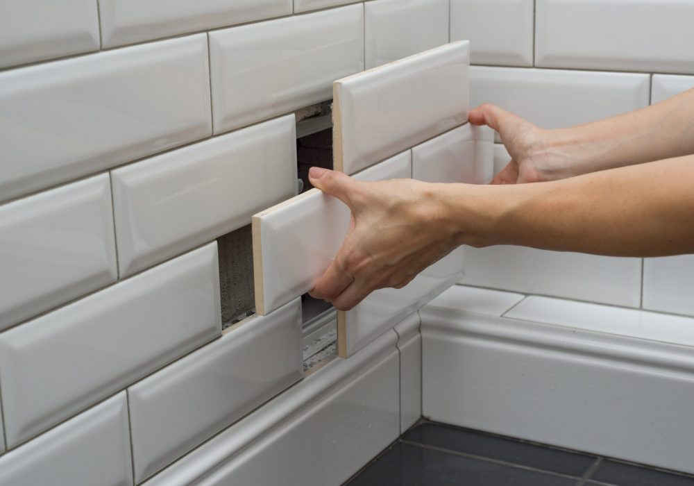 Woman opens, closes the hidden revision sanitary hatch on the wall of tile under the bathroom